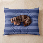 Cama azul a rayas con perro acurrucado sobre suelo de piedra