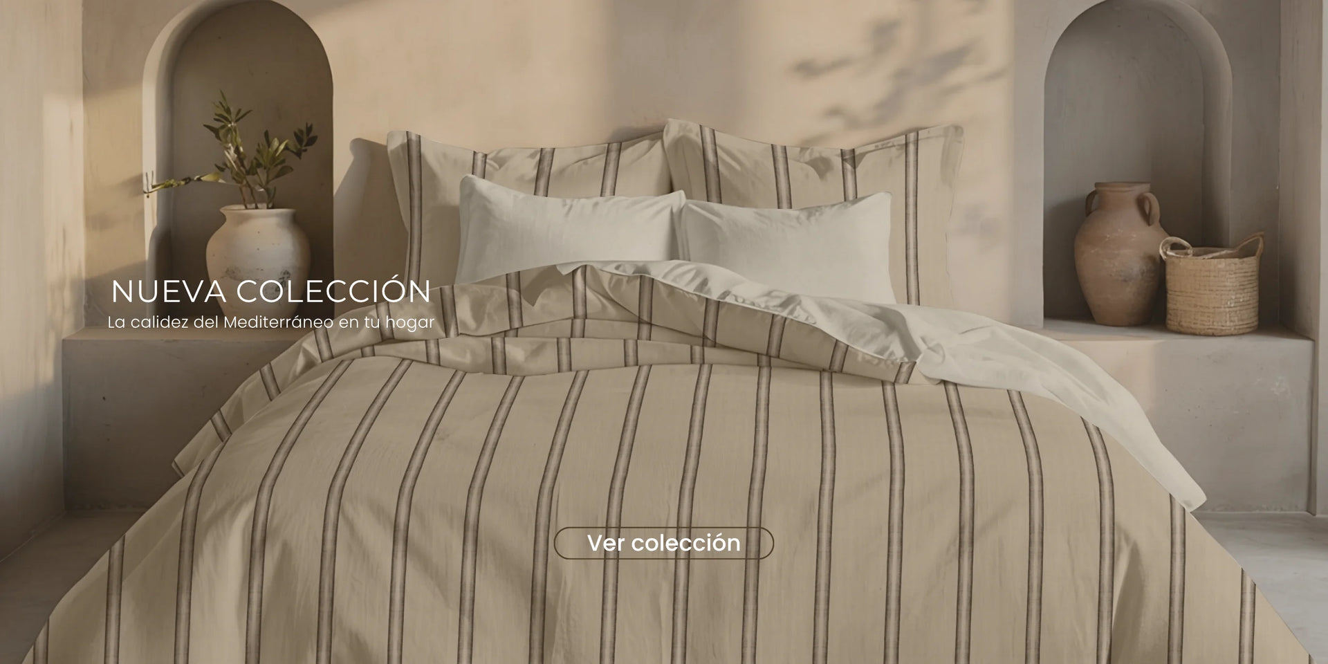 Dormitorio mediterráneo con cama vestida con funda nórdica de rayas beige, cojines blancos y decoración en tonos naturales.